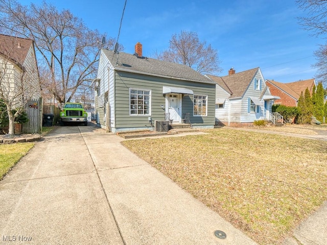 bungalow-style house with driveway, a chimney, a front lawn, and fence