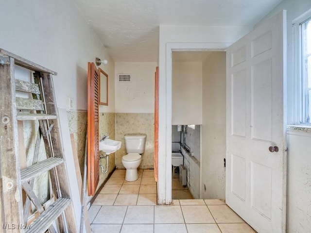 bathroom with visible vents, a wainscoted wall, toilet, tile patterned floors, and tile walls