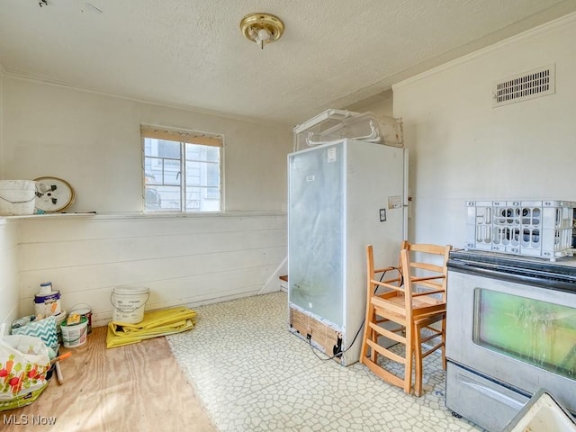 interior space featuring visible vents, wainscoting, a textured ceiling, and crown molding