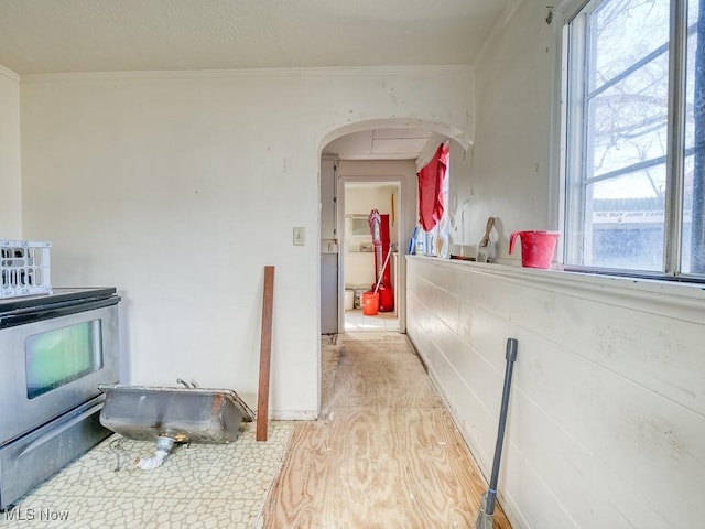 kitchen featuring wood finished floors, stainless steel electric range oven, arched walkways, and ornamental molding