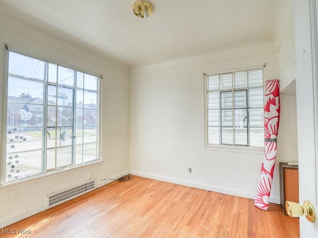 empty room featuring visible vents, baseboards, and wood finished floors