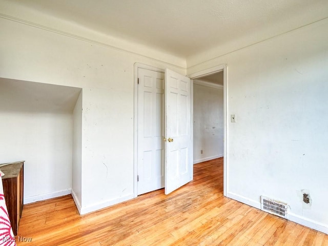 unfurnished bedroom featuring baseboards, visible vents, and light wood finished floors