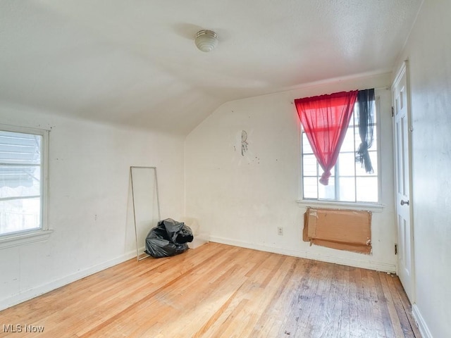 bonus room with baseboards, lofted ceiling, and hardwood / wood-style flooring