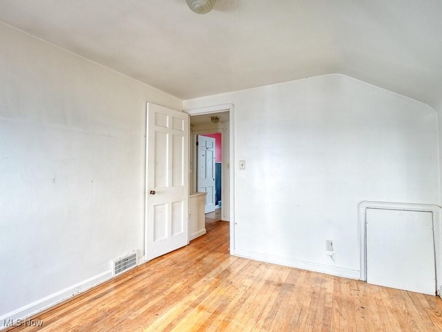 empty room with visible vents, baseboards, lofted ceiling, and hardwood / wood-style flooring