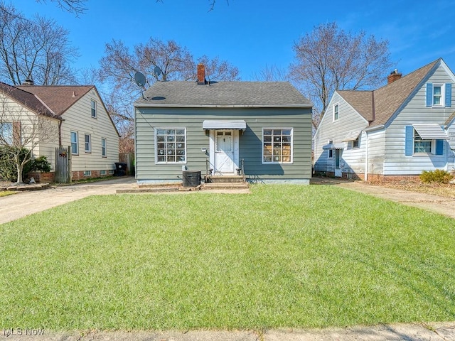 bungalow featuring central AC unit, driveway, a chimney, and a front yard