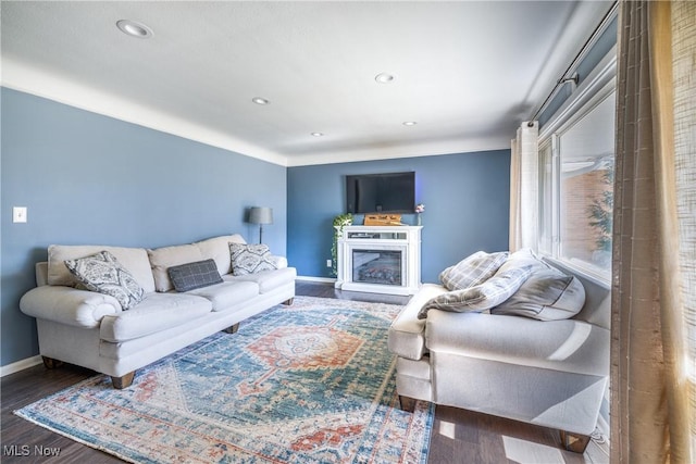 living room with a glass covered fireplace, baseboards, wood finished floors, and recessed lighting