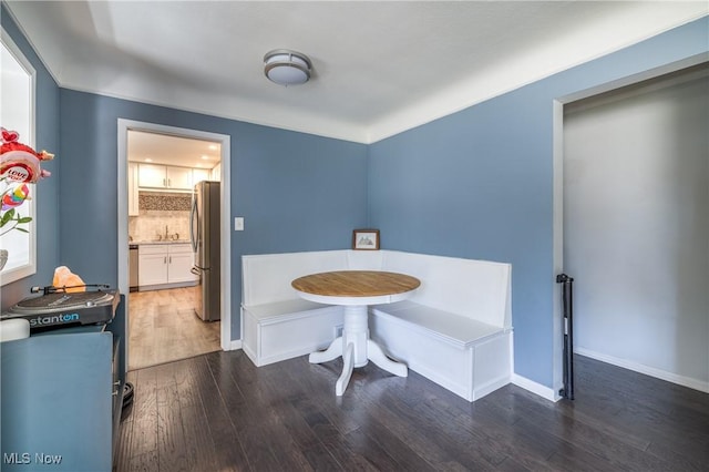 bathroom featuring wood finished floors, baseboards, backsplash, and a sink