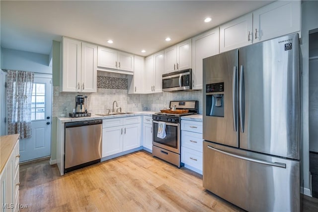 kitchen with a sink, light countertops, white cabinets, and stainless steel appliances