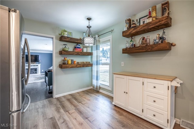 kitchen with visible vents, open shelves, light wood-style flooring, freestanding refrigerator, and white cabinets