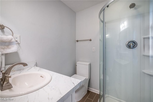 full bathroom featuring a shower stall, baseboards, wood finish floors, toilet, and a sink