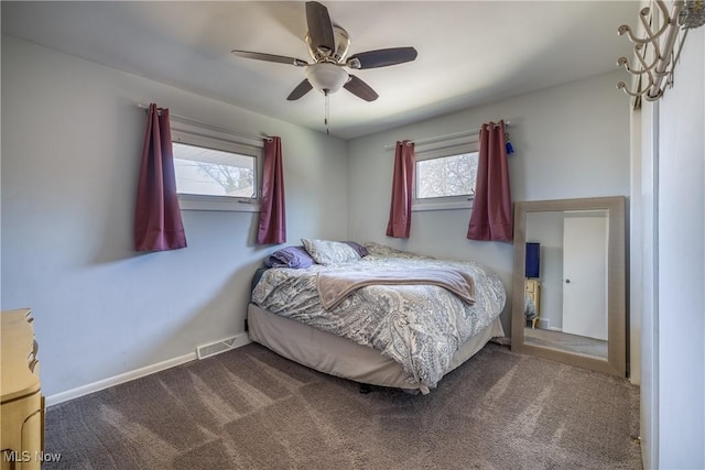 carpeted bedroom with baseboards, multiple windows, visible vents, and a ceiling fan