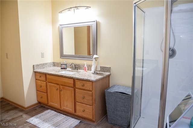 bathroom featuring a shower stall, vanity, baseboards, and wood finished floors