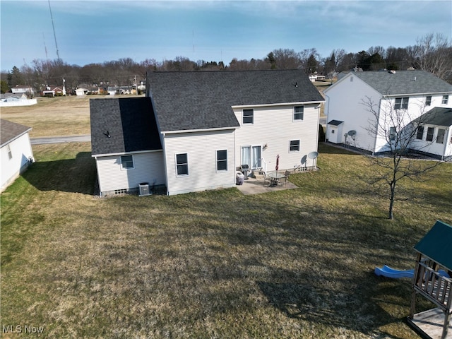 back of property with a patio area, central AC, a shingled roof, and a yard