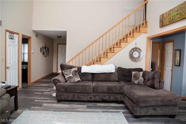 living area with stairway, a high ceiling, visible vents, and wood finished floors