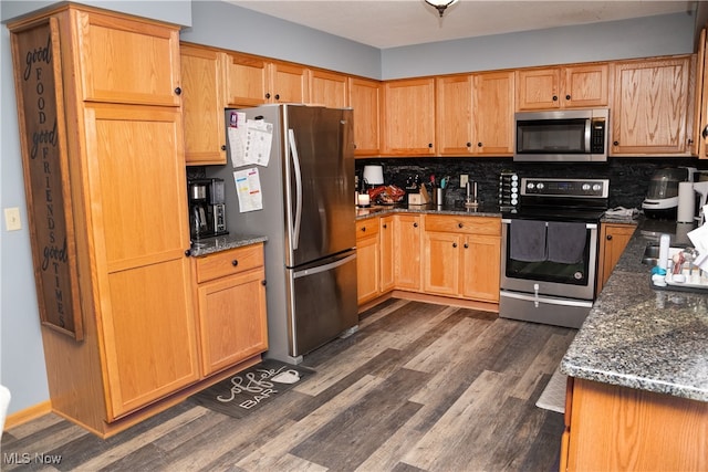 kitchen with stainless steel appliances, dark wood-style floors, decorative backsplash, and dark stone counters