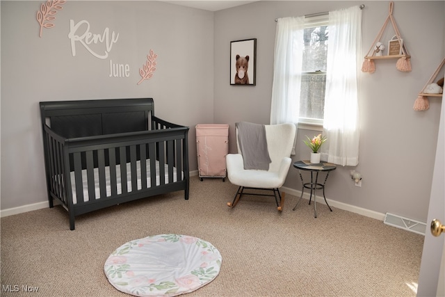 bedroom with a nursery area, carpet, visible vents, and baseboards