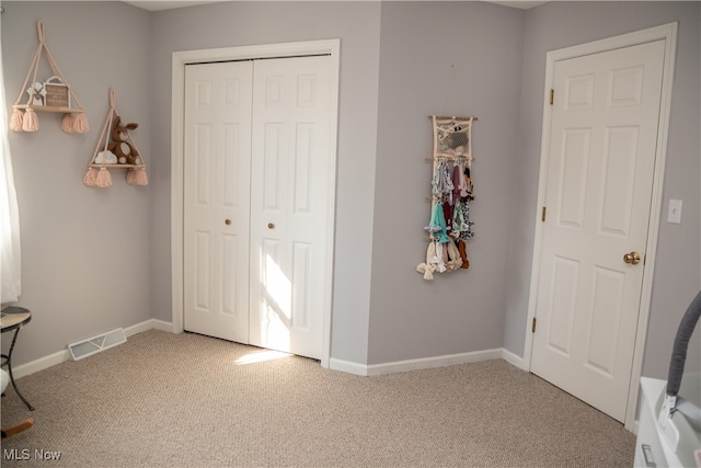 carpeted bedroom featuring baseboards, visible vents, and a closet