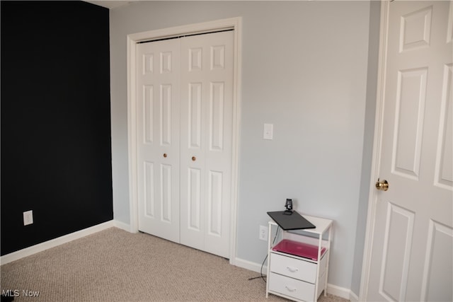 bedroom with baseboards, a closet, and light carpet