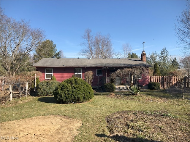 back of property with a chimney, a yard, and fence