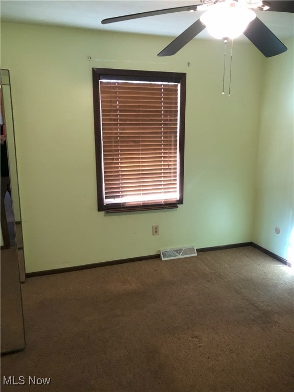 carpeted empty room with visible vents, baseboards, and ceiling fan