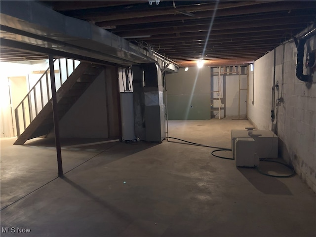 unfinished basement featuring stairs, heating unit, and water heater