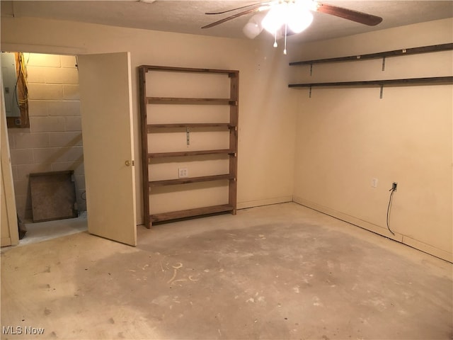 basement with concrete block wall and a ceiling fan