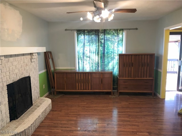 living room featuring a brick fireplace, wood finished floors, baseboards, and ceiling fan