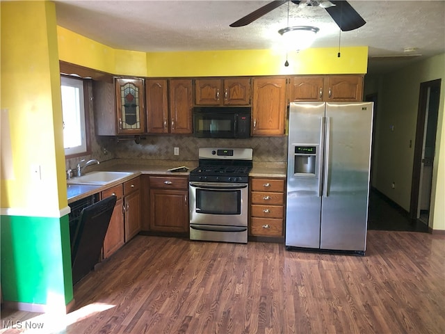 kitchen with dark wood-type flooring, a ceiling fan, appliances with stainless steel finishes, and a sink