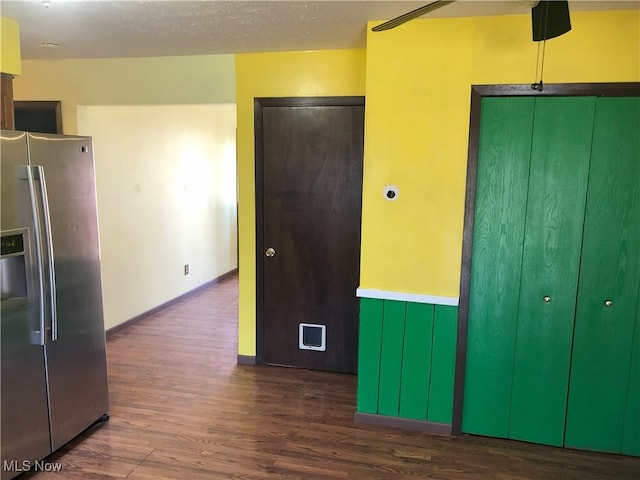 interior space featuring a wainscoted wall, a textured ceiling, wood finished floors, and stainless steel refrigerator with ice dispenser