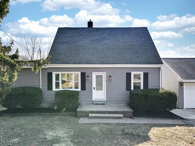 view of front facade featuring a front yard, a chimney, and a shingled roof