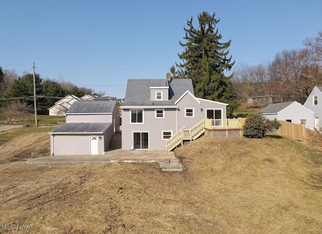 rear view of house with an outdoor structure, a wooden deck, a garage, a chimney, and a patio area