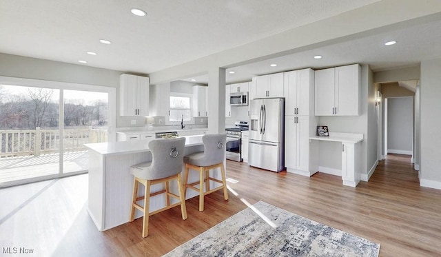 kitchen featuring a breakfast bar area, white cabinetry, stainless steel appliances, and light wood-style floors