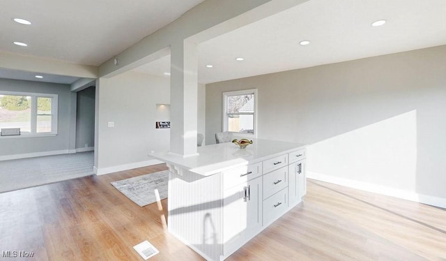 kitchen with white cabinets, recessed lighting, baseboards, and light wood-type flooring