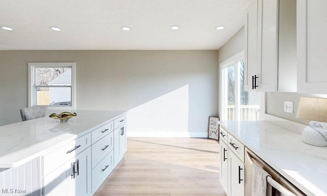 kitchen with recessed lighting, white cabinets, light wood-type flooring, and light stone countertops