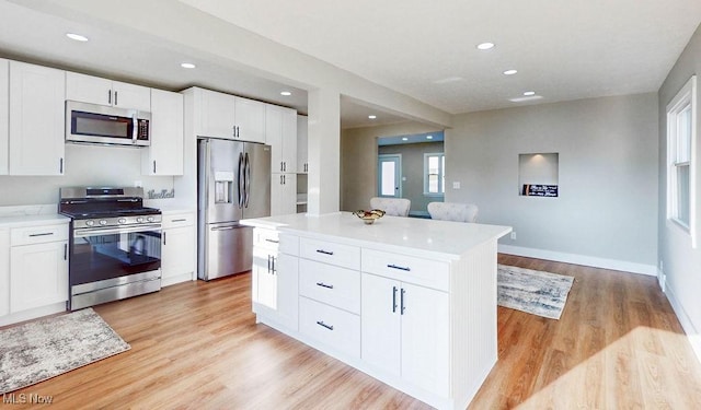 kitchen with baseboards, light wood-type flooring, recessed lighting, appliances with stainless steel finishes, and white cabinets