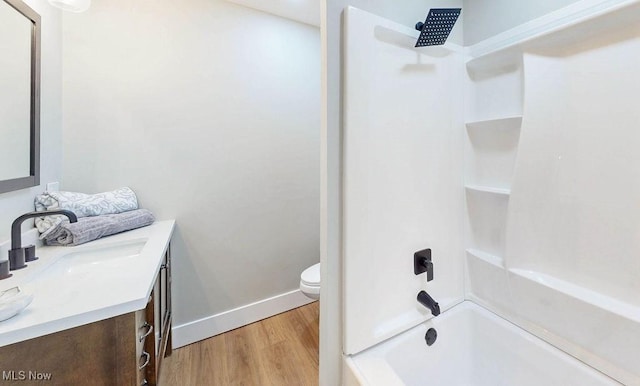 full bathroom with baseboards, toilet, bathtub / shower combination, wood finished floors, and vanity