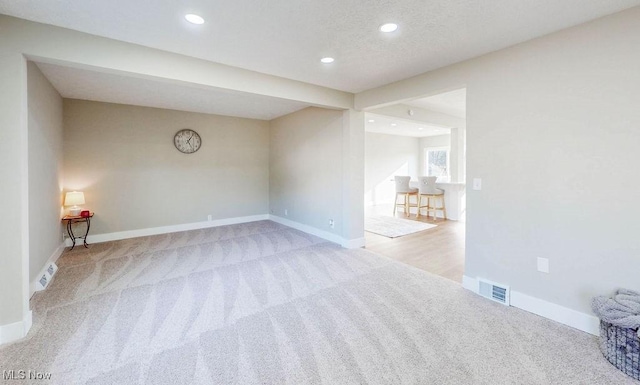 carpeted spare room featuring a textured ceiling, recessed lighting, visible vents, and baseboards