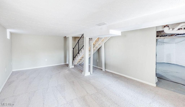 finished basement featuring carpet flooring, a textured ceiling, stairs, and baseboards