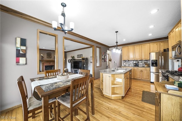 kitchen with an island with sink, a sink, appliances with stainless steel finishes, a notable chandelier, and light wood-type flooring