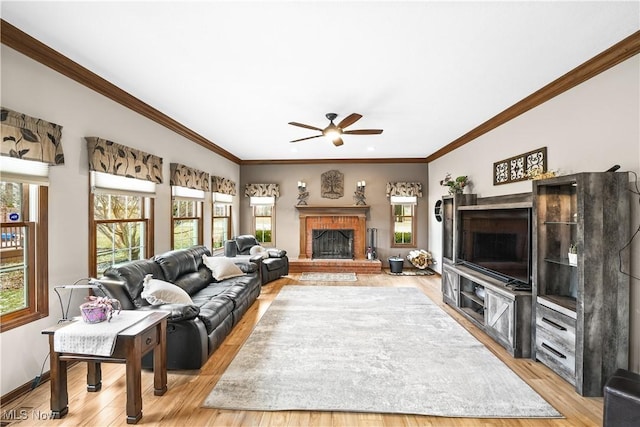 living area featuring baseboards, a fireplace, light wood-type flooring, and ceiling fan