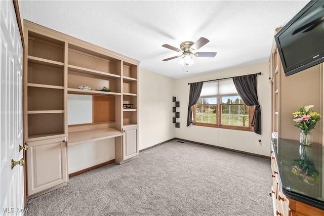 interior space with baseboards, carpet floors, and a ceiling fan