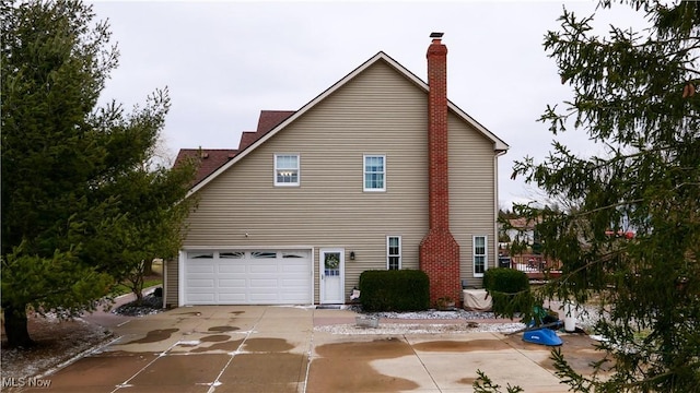 exterior space featuring an attached garage, a chimney, and concrete driveway