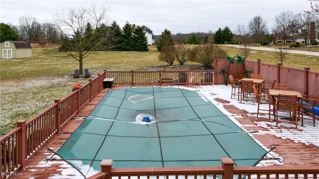 view of pool featuring fence, an outdoor structure, a patio area, a storage shed, and a lawn