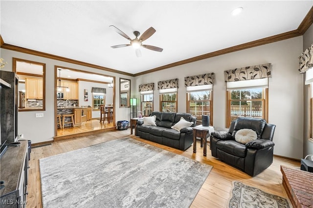 living area featuring light wood-style flooring, a ceiling fan, baseboards, and ornamental molding