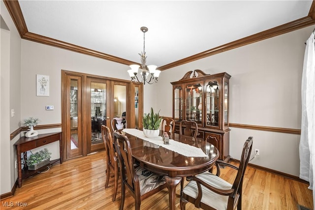 dining room featuring baseboards, light wood-type flooring, an inviting chandelier, and ornamental molding