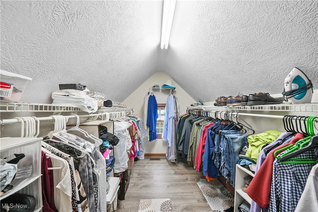 spacious closet with lofted ceiling and wood finished floors