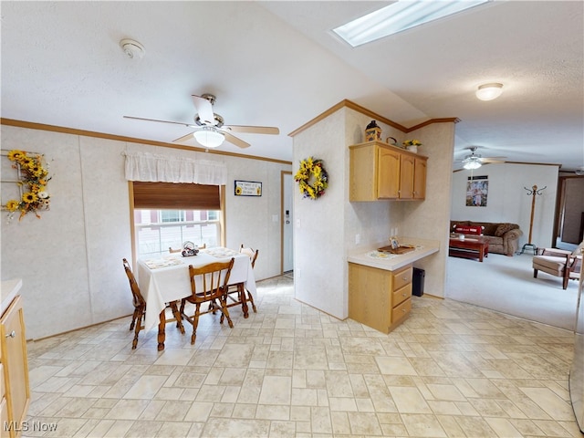 kitchen with ornamental molding, a ceiling fan, open floor plan, a skylight, and light countertops