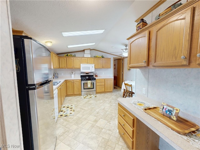 kitchen featuring ceiling fan, light brown cabinetry, light countertops, appliances with stainless steel finishes, and lofted ceiling with skylight