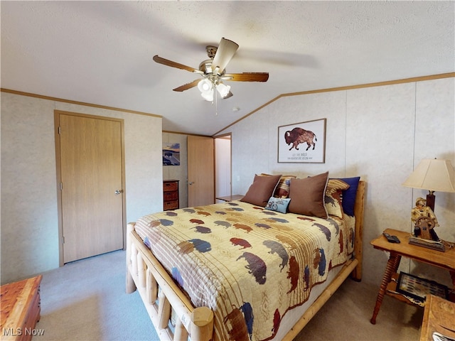 carpeted bedroom with a textured ceiling, ornamental molding, a ceiling fan, and vaulted ceiling