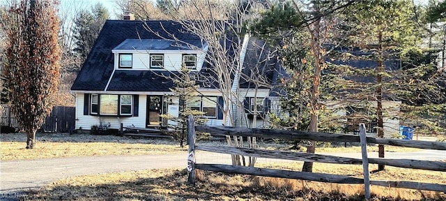 view of front facade featuring a chimney and fence